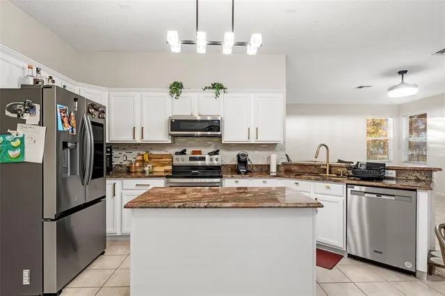 a kitchen with kitchen island granite countertop a sink appliances and cabinets