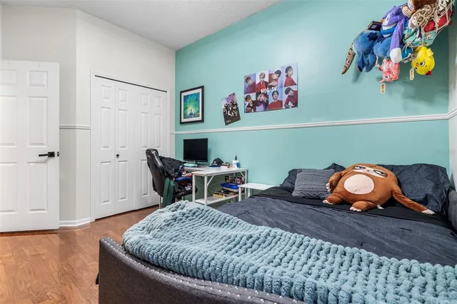 a bed room with a bed a desk and painting on the wall