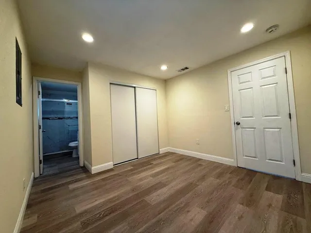 an empty room with wooden floor & closet area