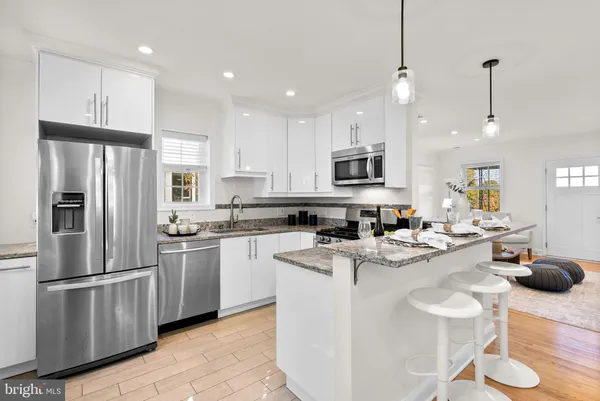 a kitchen with kitchen island a white counter top space stainless steel appliances and cabinets