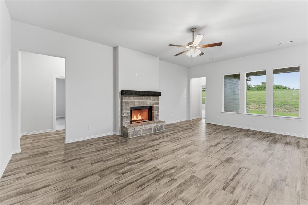 119 Hillview Trail Decatur, TX 76234 - Photo 20 of 30 Living room featuring a stone-clad fireplace with a dark mantel, wood-finish flooring, and multiple windows