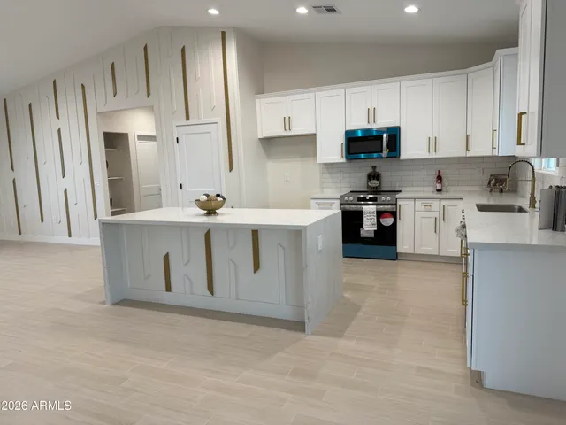 a kitchen with stainless steel appliances granite countertop a white cabinets a sink a stove a refrigerator and cabinets