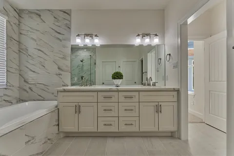 a bathroom with a granite countertop sink a large mirror and a bathtub with shower