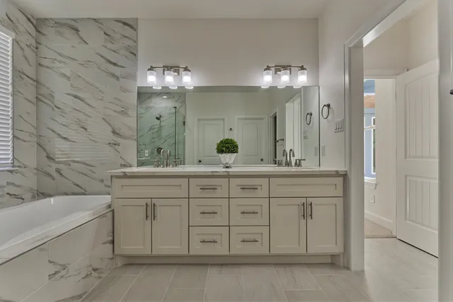 a bathroom with a granite countertop sink a large mirror and a bathtub with shower