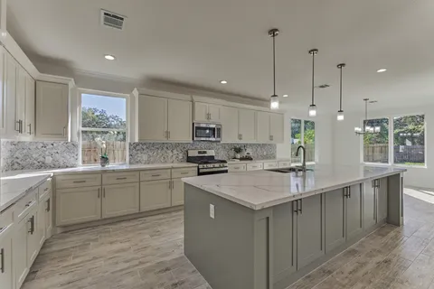 a kitchen with stainless steel appliances granite countertop a sink a stove a refrigerator a center island and cabinets