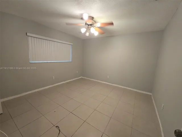 an empty room with a chandelier fan and windows