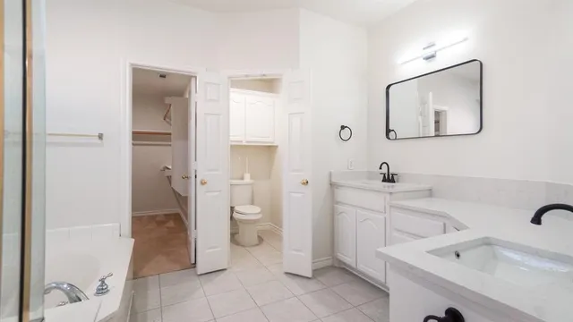 a spacious bathroom with a toilet sink and mirror