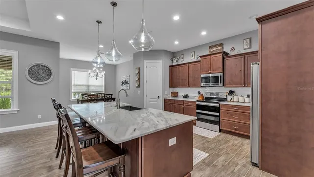 a kitchen with kitchen island granite countertop a dining table chairs refrigerator and cabinets