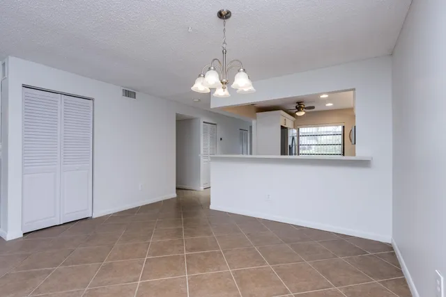 a view of a room with a chandelier fan and kitchen view