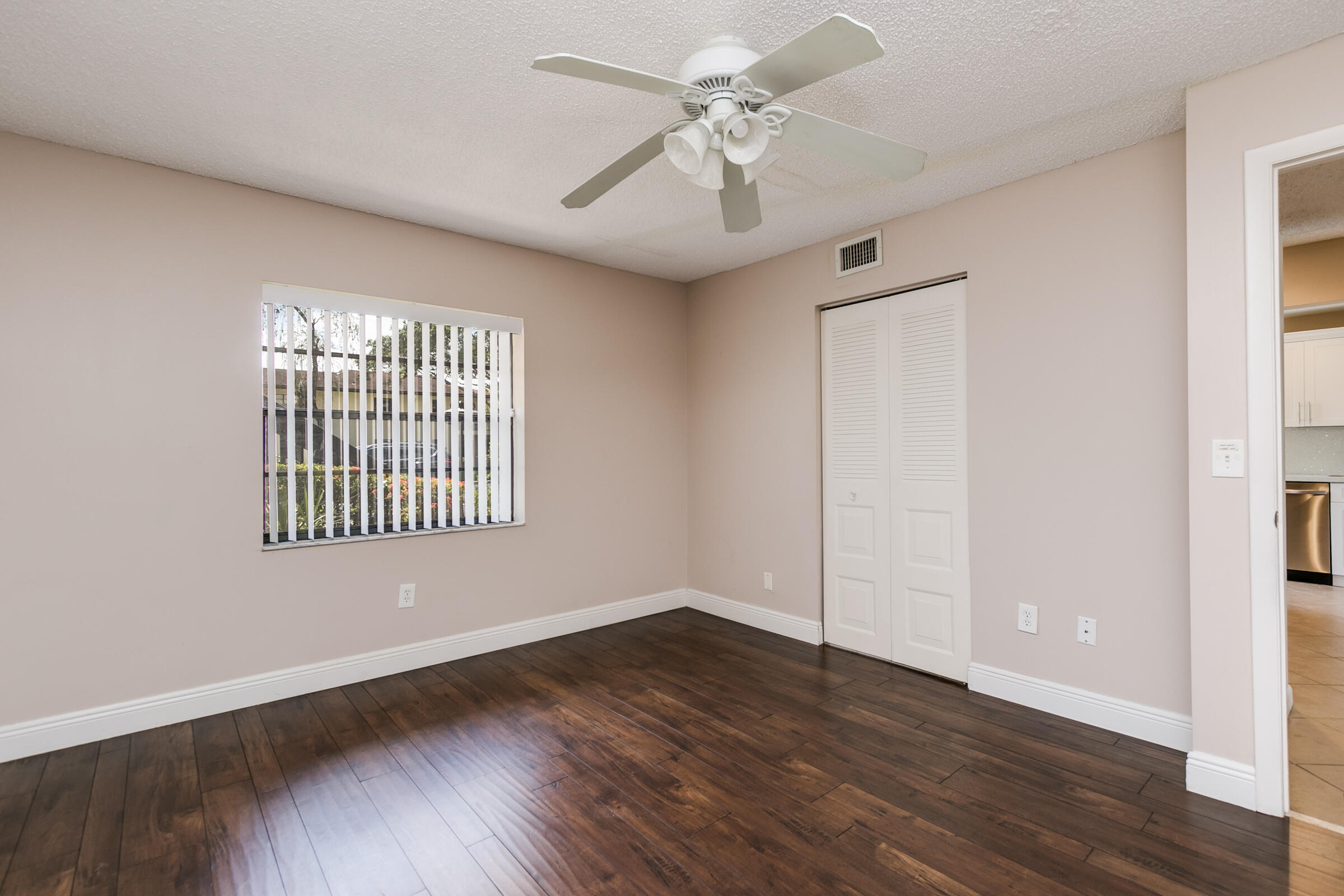 8535 Casa Del Lago, Unit 37E Boca Raton, FL 33433 - Photo 17 of 39 an empty room with wooden floor chandelier fan and windows