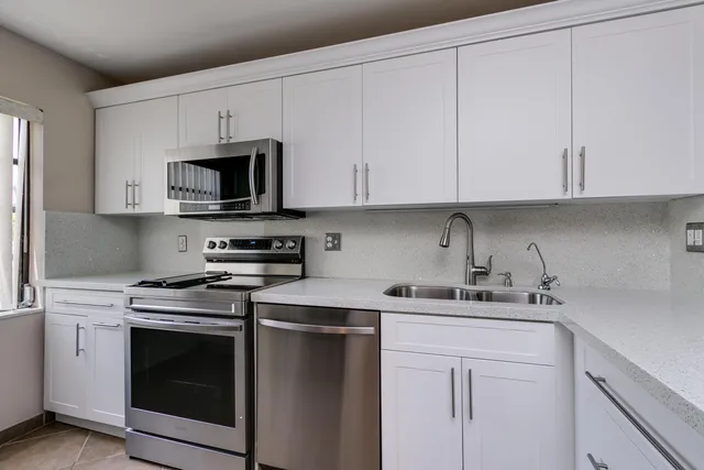 a kitchen with cabinets appliances a sink and a counter top