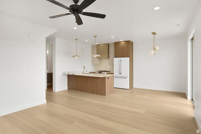 990 Manen Street Washington, UT 84780 - Photo 12 of 43 Modern kitchen featuring an island with a light-toned countertop, stainless steel appliances, contemporary pendant lighting, and warm wood-finish flooring