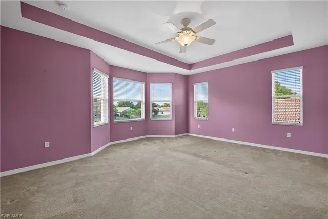 a view of an empty room with chandelier fan and a large window