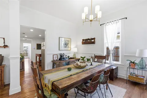 a dining room with wooden floor a chandelier a wooden table and chairs
