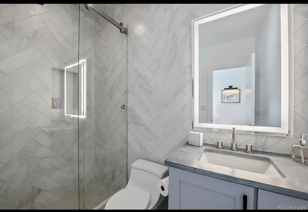 a bathroom with a granite countertop toilet sink and mirror