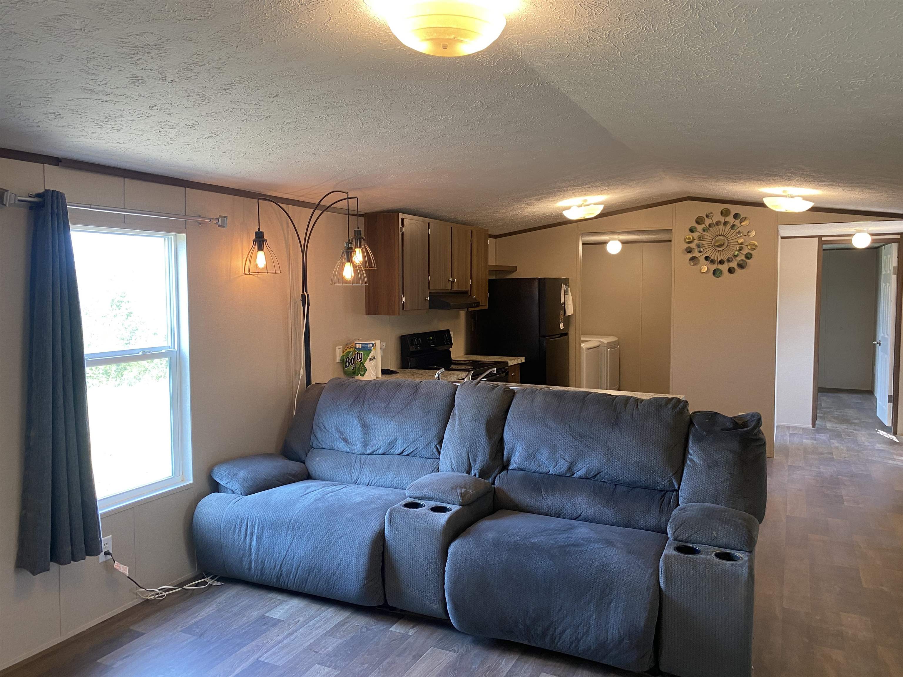 7080 Beauty Hill Road Adamsville, TN 38310 - Photo 11 of 37 Living room with lofted ceiling, hardwood / wood-style floors, a textured ceiling, and a healthy amount of sunlight