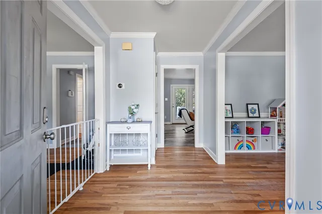 a view of a hallway to a livingroom with wooden floor and furniture