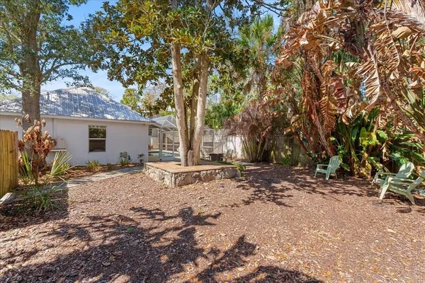 a backyard of a house with large trees and outdoor seating