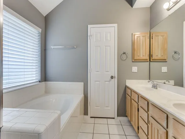 a spacious bathroom with a tub sink and mirror