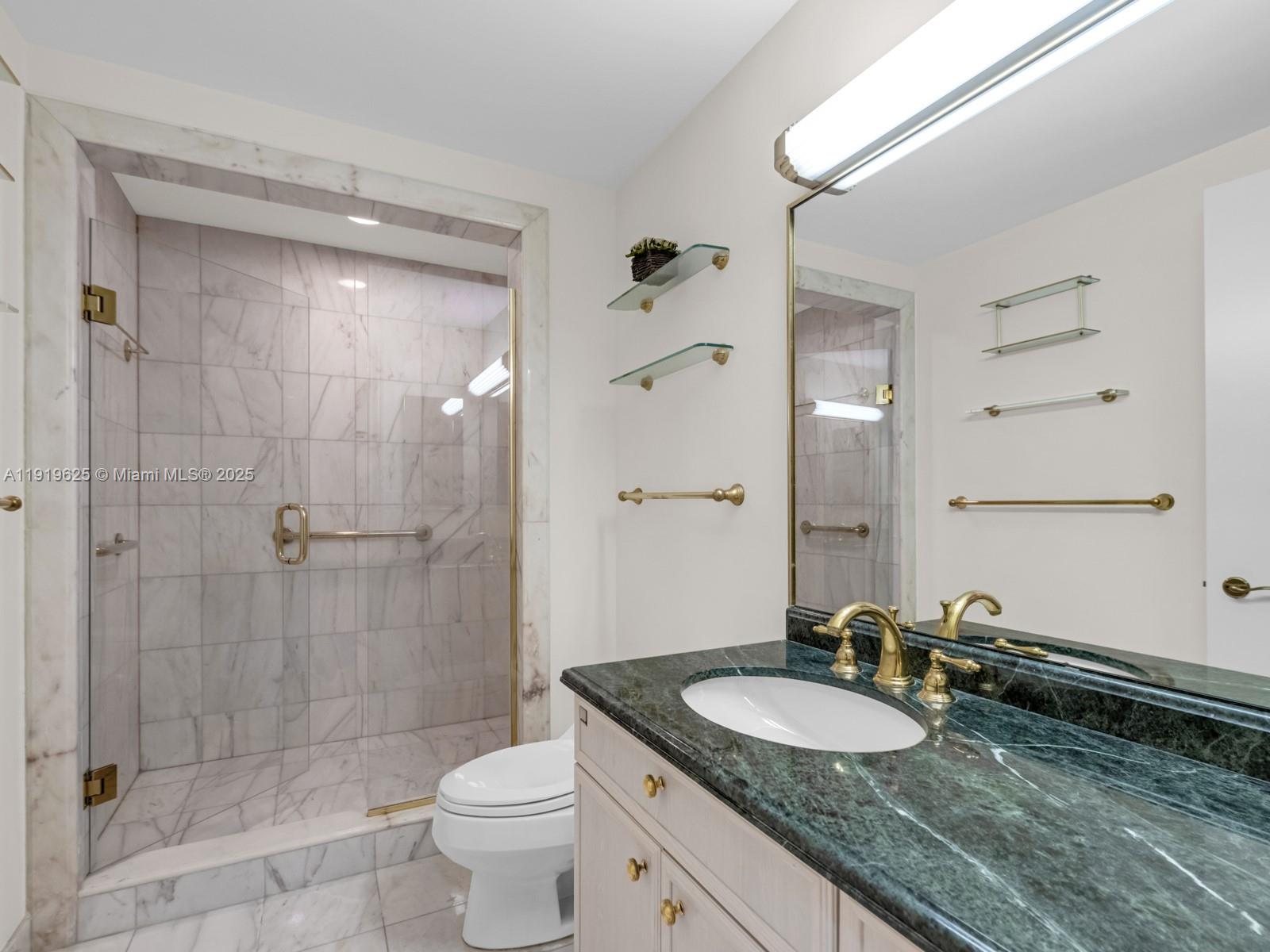 445 Grand Bay Drive, Unit 303 Key Biscayne, FL 33149 - Photo 45 of 52 a bathroom with a granite countertop sink a toilet a mirror and shower