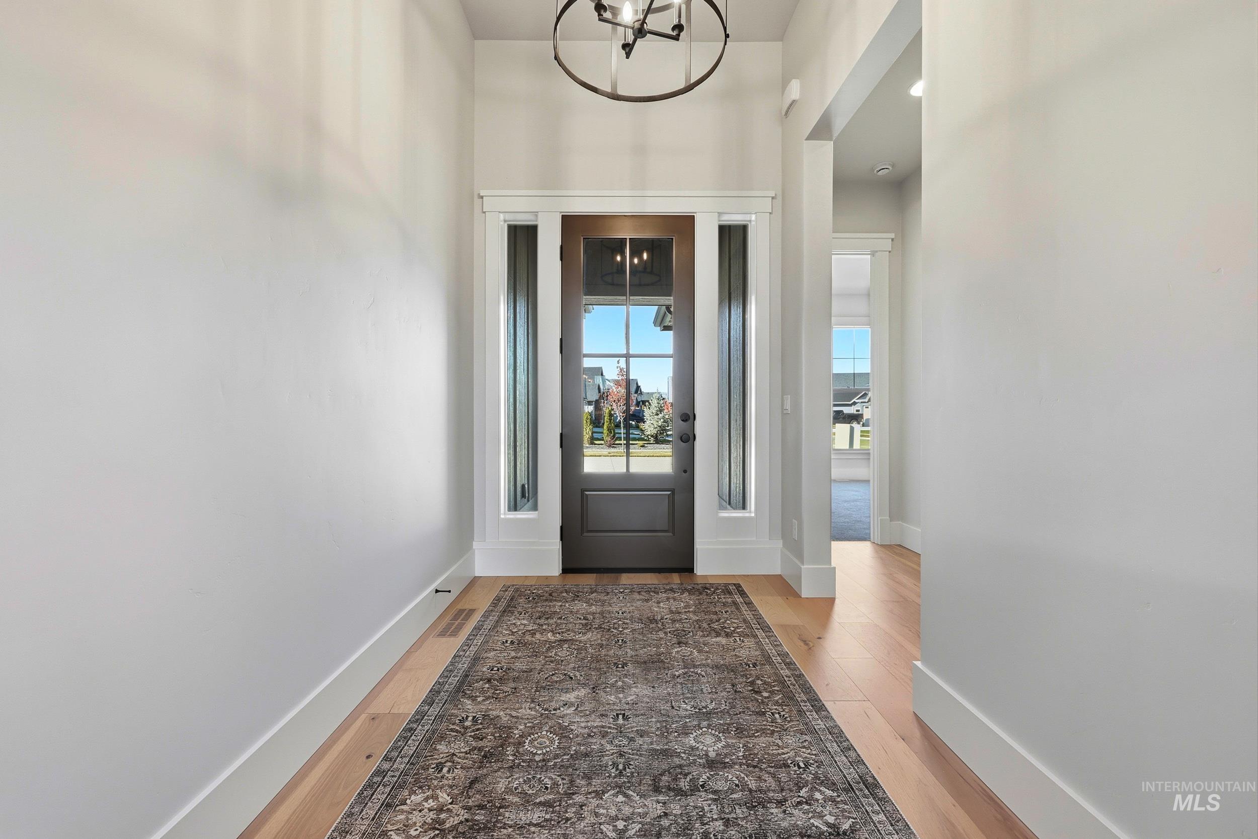 6771 South Messner Way Meridian, ID 83642 - Photo 33 of 45 Doorway to outside with wood finished floors and a chandelier