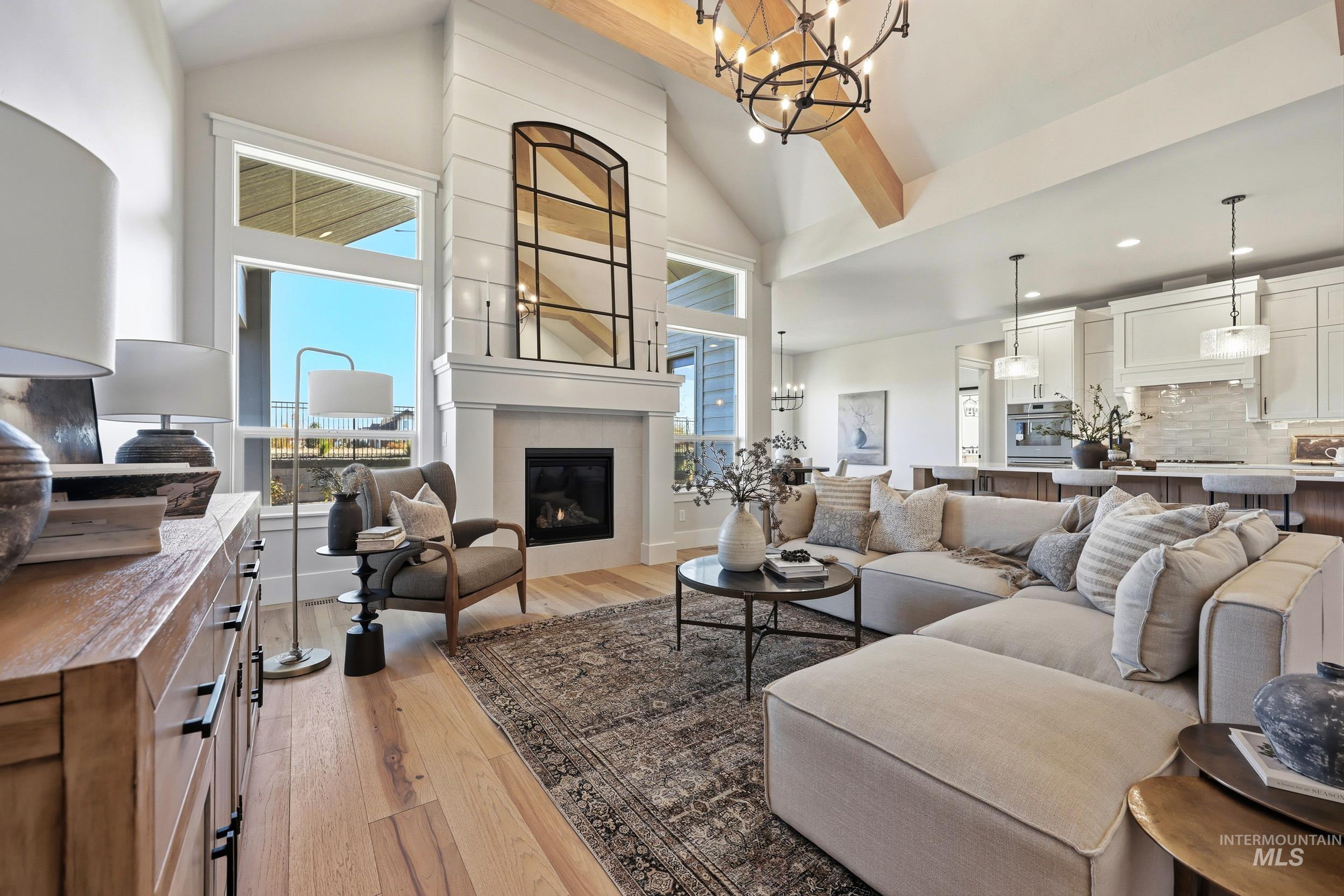 6771 South Messner Way Meridian, ID 83642 - Photo 9 of 45 Living area featuring a chandelier, light wood-style floors, high vaulted ceiling, and a fireplace