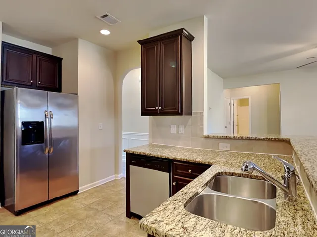 a kitchen with stainless steel appliances granite countertop a sink a refrigerator and a microwave