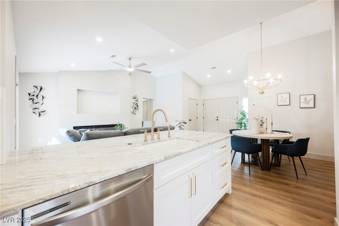 9337 Quail Ridge Drive Las Vegas, NV 89134 - Photo 19 of 28 Kitchen featuring dishwasher, light stone countertops, light wood-style flooring, vaulted ceiling, and hanging light fixtures