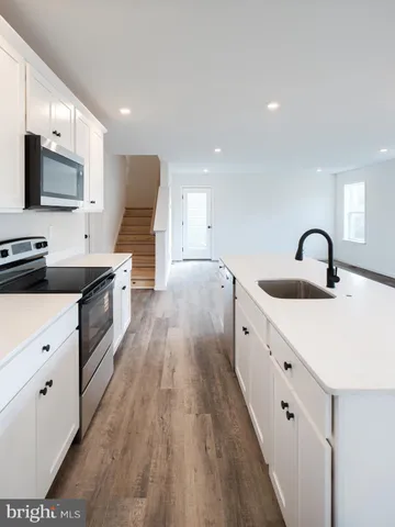 a large white kitchen with a large window a sink and stainless steel appliances