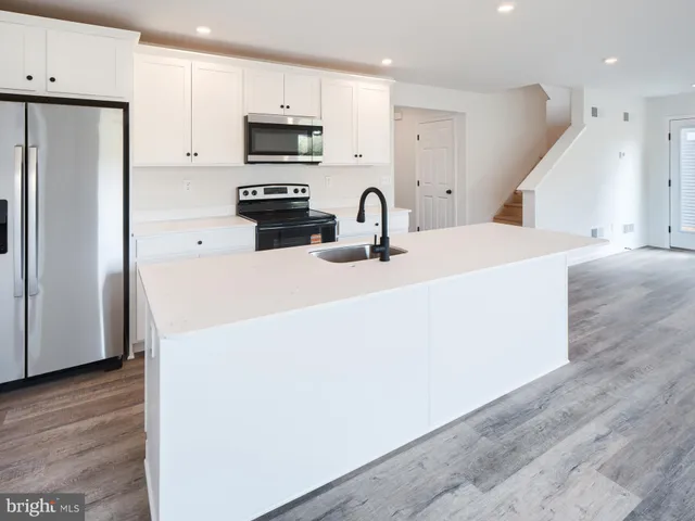 a kitchen with kitchen island a white counter top space cabinets and stainless steel appliances