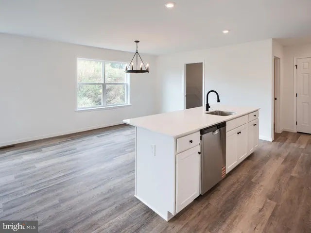 a utility room with stainless steel appliances wooden floors and white walls