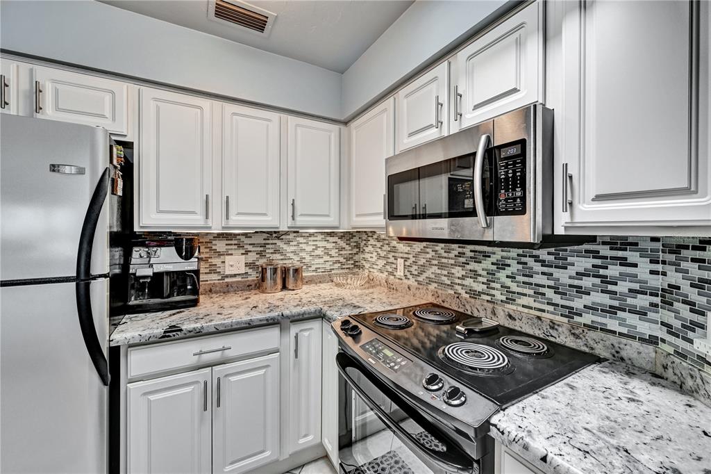 5854 Gasparilla Road, Unit M22 Boca Grande, FL 33921 - Photo 15 of 54 a kitchen with stainless steel appliances granite countertop cabinets and a stove top oven