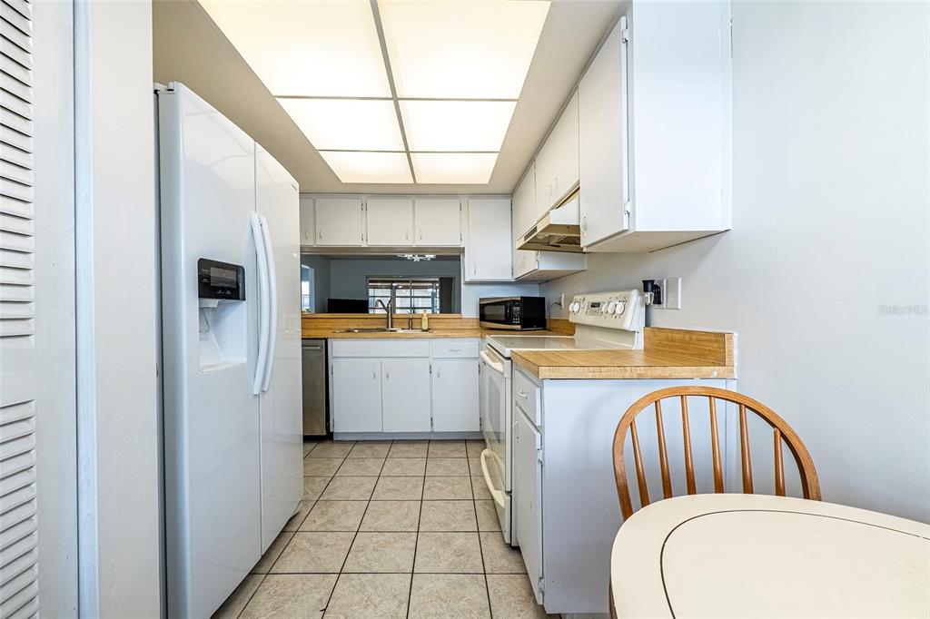 5197 Silent Loop, Unit 224 New Port Richey, FL 34652 - Photo 7 of 41 a kitchen with stainless steel appliances a white refrigerator a sink dishwasher and white cabinets with wooden floor