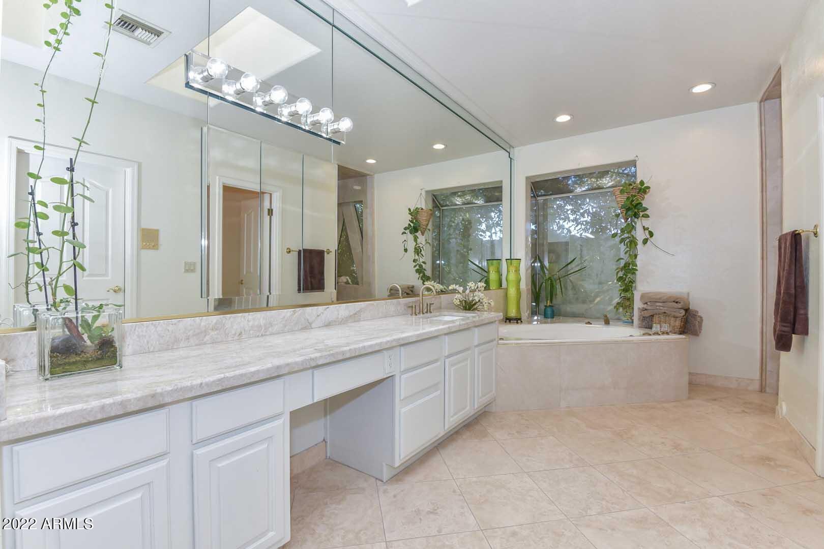 5237 North 106th Avenue Glendale, AZ 85307 - Photo 19 of 75 a bathroom with a granite countertop sink a large mirror and a bathtub next to a window