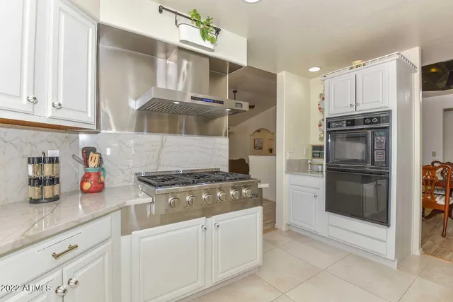 a kitchen with granite countertop a refrigerator and a stove top oven