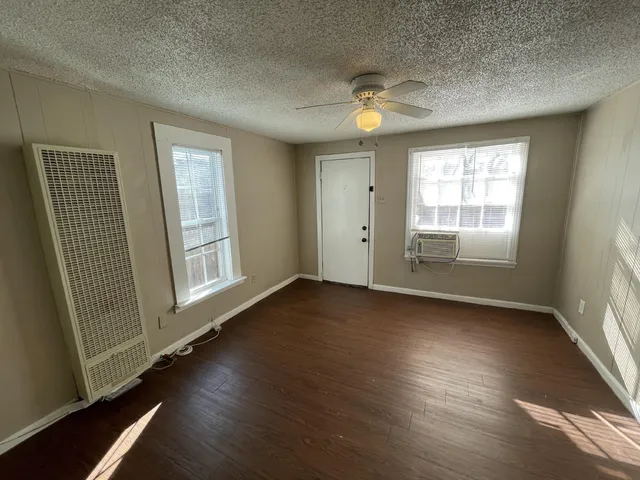 an empty room with wooden floor and windows