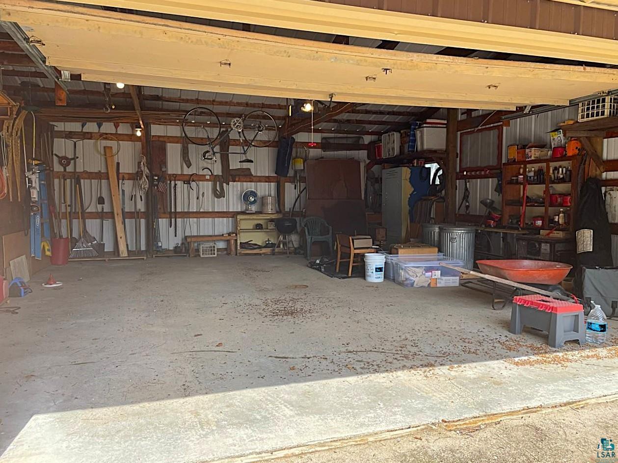 1480 Maijala Road Ely, MN 55731 - Photo 38 of 58 Spacious 24' x 26' garage bay featuring a concrete floor, exposed wood beam construction, corrugated metal wall panels, and overhead lighting