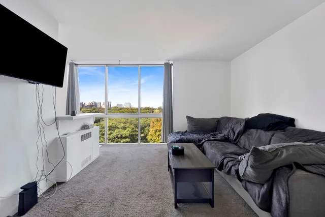 a living room with furniture a flat screen tv and a refrigerator