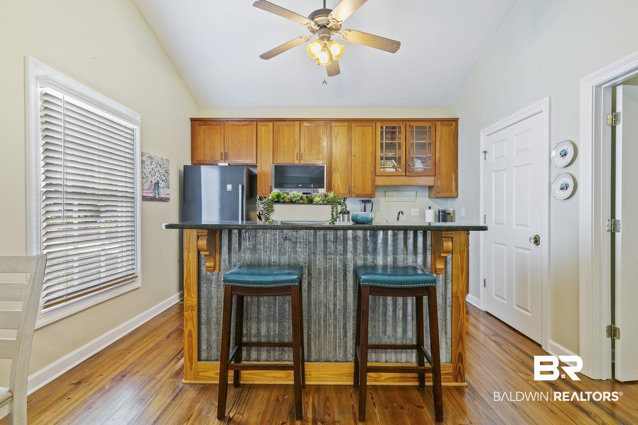 17341 Cabin Road Loxley, AL 36551 - Photo 18 of 49 Kitchen featuring hardwood / wood-style flooring, stainless steel refrigerator, a breakfast bar, and lofted ceiling
