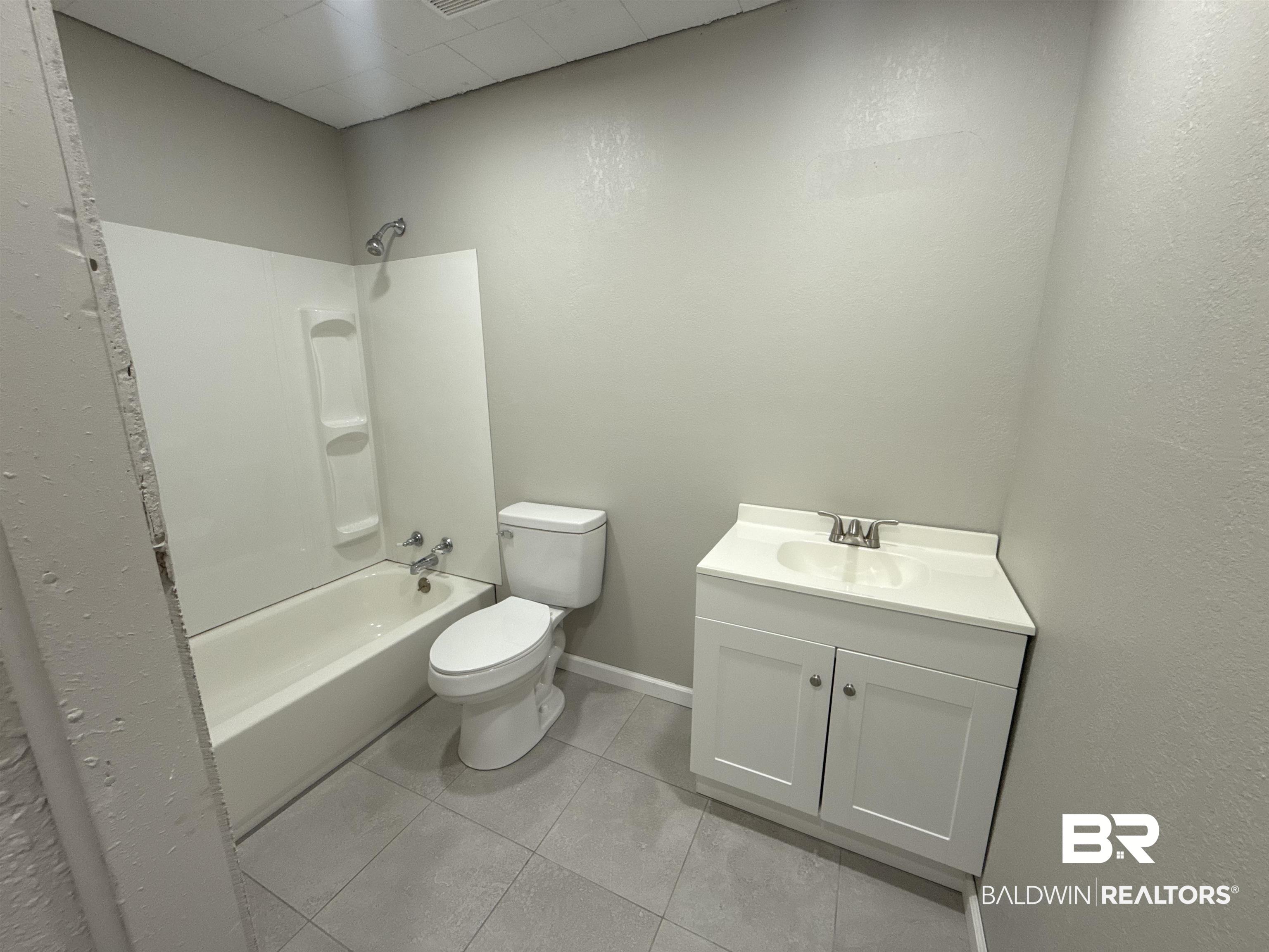 32 Slate Street Atmore, AL 36502 - Photo 9 of 16 Bathroom with vanity, shower / bath combination, and light tile patterned flooring