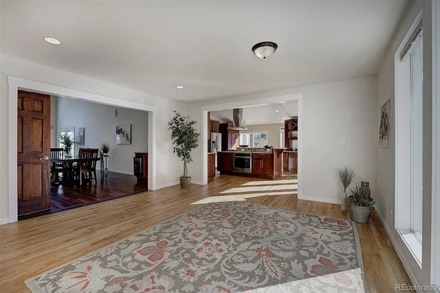 a living room with furniture a dining table and a large window with wooden floor