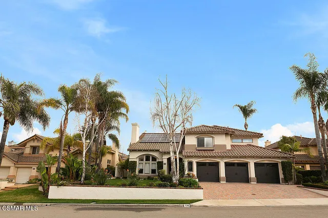 a front view of a white house with a palm tree