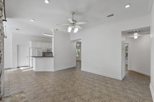 a kitchen with granite countertop a refrigerator a stove a sink and white cabinets