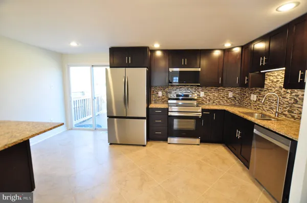 a kitchen with stainless steel appliances granite countertop a refrigerator a stove a sink and a oven