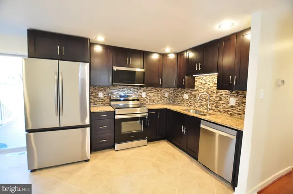 a kitchen with stainless steel appliances granite countertop a refrigerator a stove and a sink