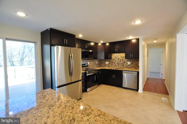 a kitchen with stainless steel appliances kitchen island granite countertop a refrigerator and a sink