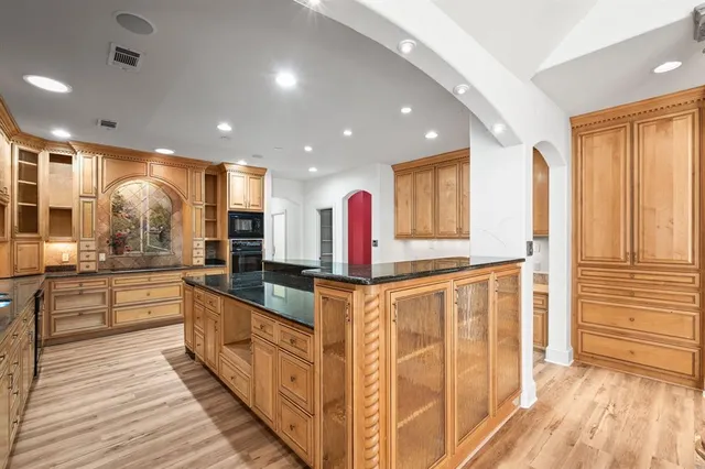a large kitchen with stainless steel appliances granite countertop a large counter top and a wooden floors
