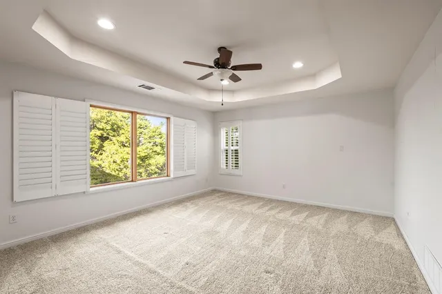 an empty room with windows and ceiling fan