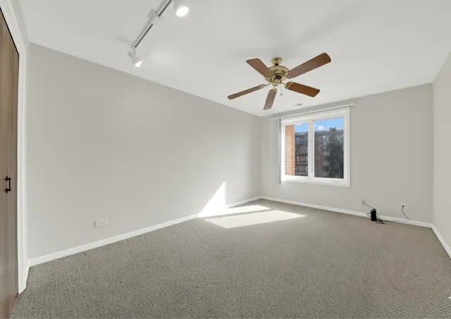an empty room with a window and a ceiling fan