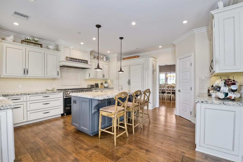 1494 Meredith Road Fallbrook, CA 92028 - Photo 26 of 47 a kitchen with stainless steel appliances kitchen island granite countertop a table chairs sink and cabinets